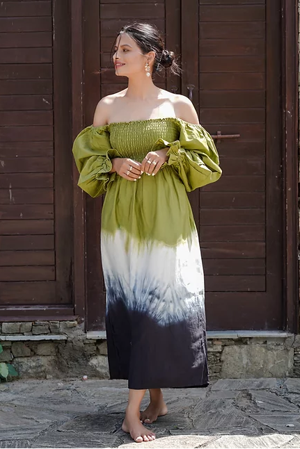 A woman standing in front of a door, wearing a green and black tie-dye midi dress with three-quarter sleeves and a V-neckline.